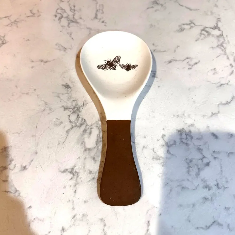 white ceramic spoon rest black bee graphic contrasting brown dipped handle